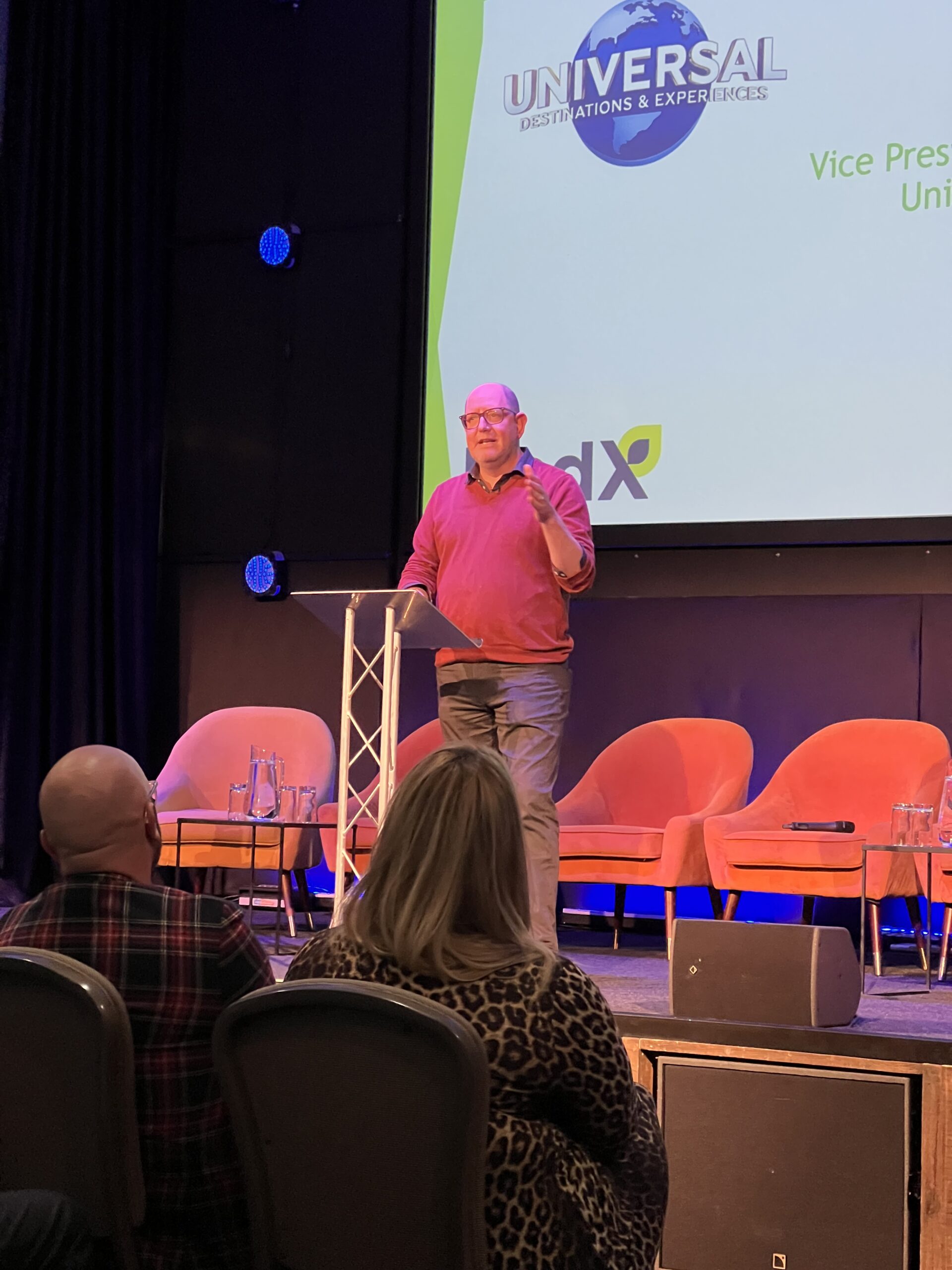 Gidon Freeman speaking at the lectern in front of the Universal Destinations and Experiences slide.